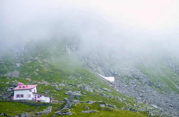 Vadideki yalnız ev Fagaras dağları, dağlardaki yalnız ev kızıl kisha ile, manzara sisle kaplıdır. Dağlar sisi kapladı..