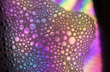 Renkli kombinasyonlu bir su yüzeyine renkli yağ damlaları