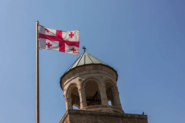 Temple tower and Georgian flag on sky background