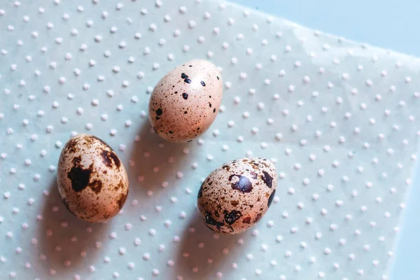 Bıldırcın yumurtaları mavi bir arkaplanda kağıt peçetenin üzerinde yatar..
