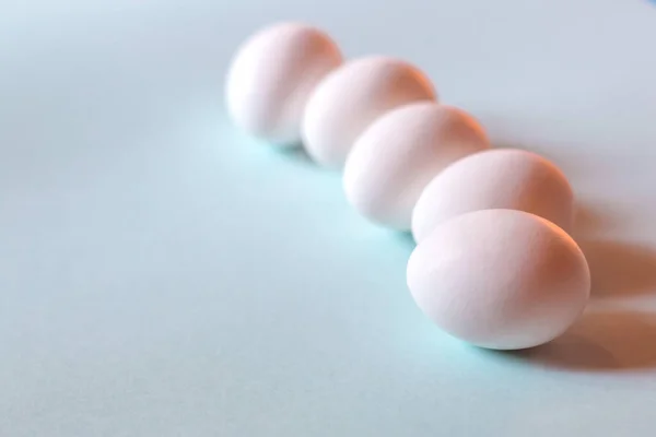 Beyaz tavuk yumurtaları mavi arka planda yatar..