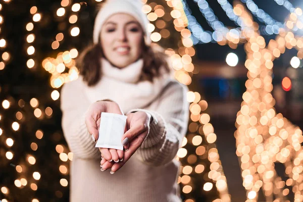 Girl hold hand warmers on night lights background.