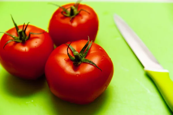 Yeşil kesme tahtasıüzerinde kırmızı domates.