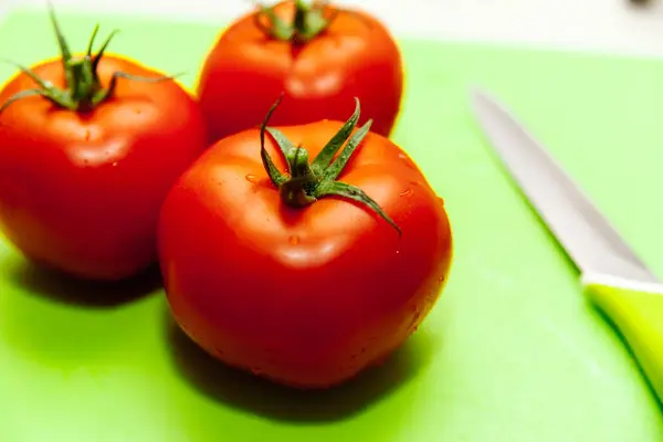 Yeşil kesme tahtasıüzerinde kırmızı domates.