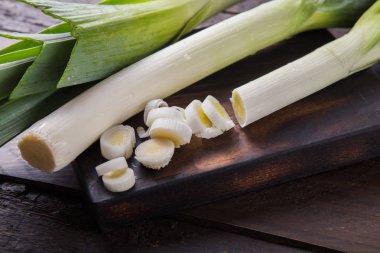 Ahşap arka planda taze çiğ pırasa dilimleri. Olgun soğan