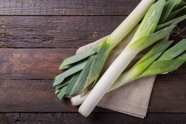 Ahşap arka planda taze çiğ pırasa dilimleri. Olgun soğan
