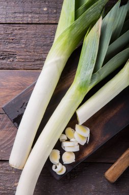 Ahşap arka planda taze çiğ pırasa dilimleri. Olgun soğan