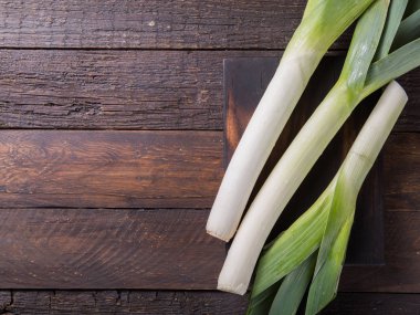 Ahşap arka planda taze çiğ pırasa dilimleri. Olgun soğan
