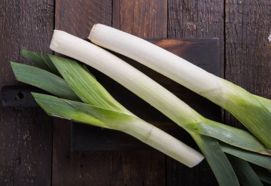 Ahşap arka planda taze çiğ pırasa dilimleri. Olgun soğan