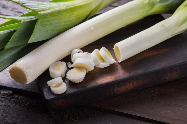 Ahşap arka planda taze çiğ pırasa dilimleri. Olgun soğan