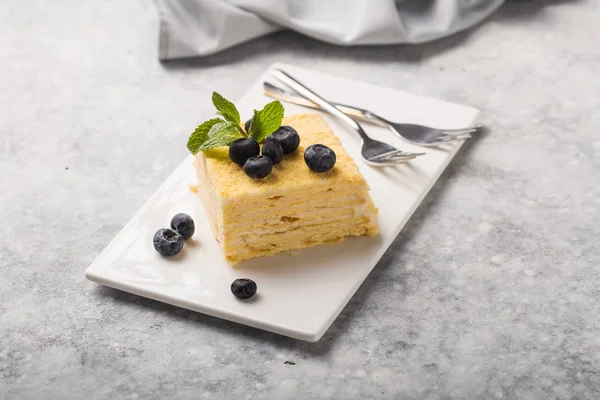 Pedazo de pastel Napoleón sobre plato blanco sobre hormigón b —  Fotos de Stock