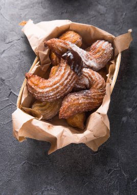 Çikolata soslu ve şekerli kâğıt torba içinde Churros.