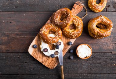 Krem peynirli bagel sandviçi ve ahşap masada yabanmersini.