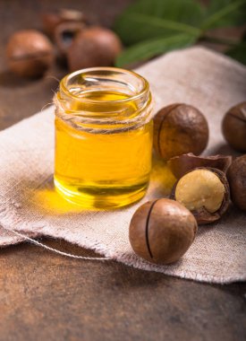 Olgun Macadamia fındığı ve doğal yağ kaynağıyla dolu cam bir şişe.