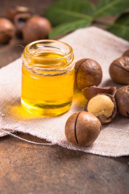 Olgun Macadamia fındığı ve doğal yağ kaynağıyla dolu cam bir şişe.