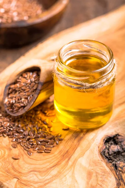 Aceite de linaza y semillas crudas sobre fondo de madera . — Foto de Stock