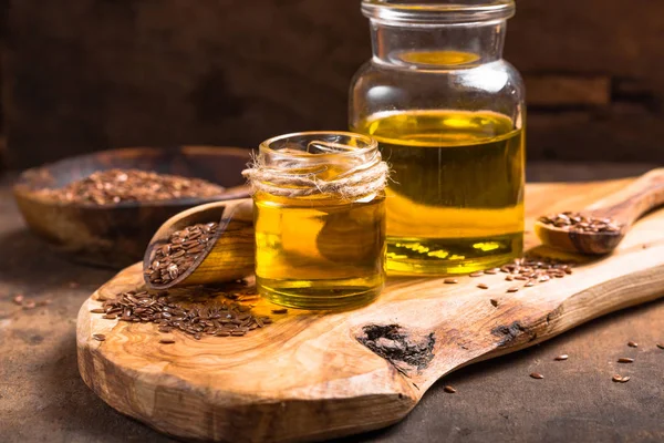 Aceite de linaza y semillas crudas sobre fondo de madera . — Foto de Stock