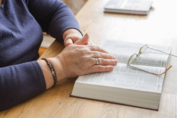 Old woman hands on the open prayer Ukraine Bible. Reading the bo
