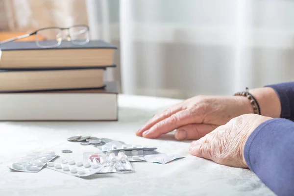 Closeup senior woman hands with pills and coins  on table at hom