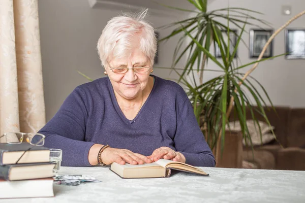 Starší žena čte soustředěné v knize v knihovně v — Stock fotografie