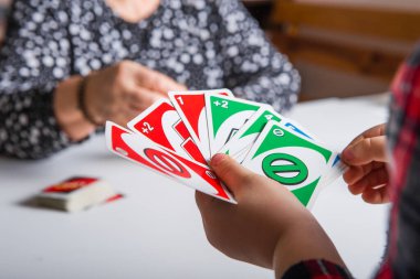 Kiev, Ukrayna - Jeniaury 31. 2020: Uno kartları elinde küçük çocuk; Amerikan kart oyunu