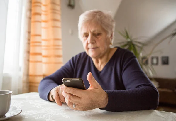 退職した女性は 居心地の良い家庭のキッチンで 携帯電話を使用しています おばあちゃんは料理にコーヒーブレイクがある 先輩はレシピを探しています インターネット上の通信 本物の瞬間 — ストック写真