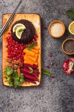 Tayland diyeti yemekleri, çiğ havuç, pancar kökü, ceviz, nar ve nane ile pişirilmiş Black Rice. Sağlıklı vejetaryen kasesi. Kopyalama alanı olan üst görünüm.