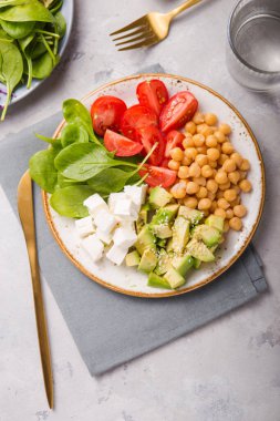 Avokado, nohut, feta peyniri, taze ıspanak, domates ve bir bardak suyla Buda Kasesi. Sağlıklı vejetaryen detoks dengeli yemek kavramı. Üst Manzara. Boşluğu kopyala.