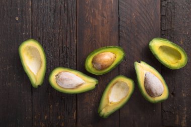 Eski ahşap masa üzerinde taze organik avokado yarıları. Fotokopi alanı ile sağlıklı gıda kavramı..