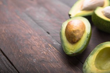 Eski ahşap masa üzerinde taze organik avokado yarıları. Fotokopi alanı ile sağlıklı gıda kavramı..