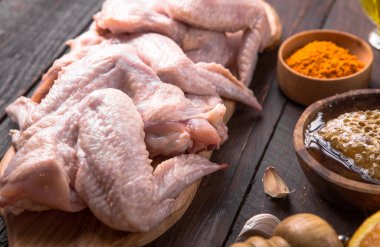 Pişirmek için malzemeli çiğ tavuk kanadı: hohey, portakal meyvesi, sarımsak, zeytin yağı, ahşap zemin üzerinde kari. Üst görünüm .