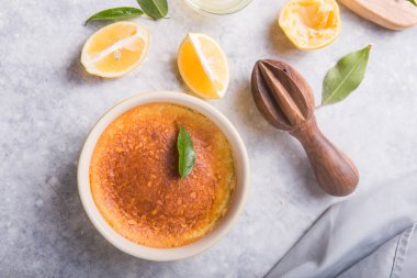 Ev yapımı güveç, puding, cheesecake, turta, turta ya da krema. Taze limon ve gri taşlı arka planda yapraklar. Meyveler ve dilimler düz yerde. Citrus arkaplanı, kopyalama alanı