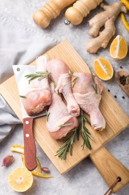 Çiğ organik tavuk budu veya tavada pişirmek için malzemelerle (biber, limon, biberiye, tuz, sarımsak). Et üst görünümü