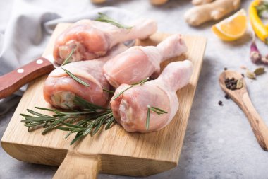 Çiğ organik tavuk budu veya tavada pişirmek için malzemelerle (biber, limon, biberiye, tuz, sarımsak). Et üst görünümü