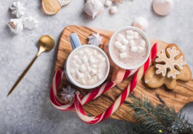 Sıcak çikolatalı kakao, gri arka planda noel renkli kupalarla marshmallowlu içecek. Geleneksel sıcak içecek, Noel 'de ya da Yeni Yıl' da festival kokteyli.