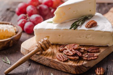 Brie peyniri ya da yumuşak inek dilimi - Fransız peyniri üzümlü, bal peteği ve cevizli ahşap panoda..