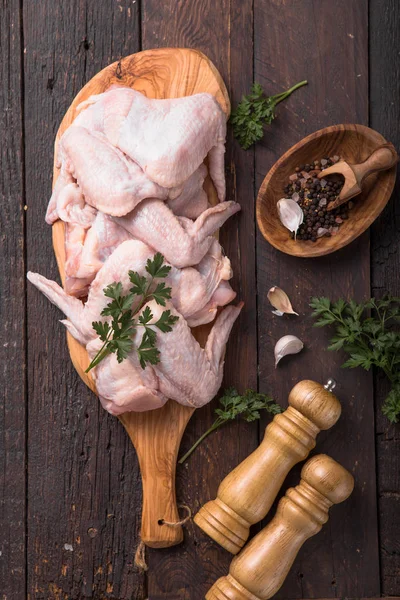 調理のための成分と生の鶏の羽 木製の背景に木製のまな板上の蜂蜜 オレンジフルーツ ニンニク オリーブオイル トップ表示 — ストック写真