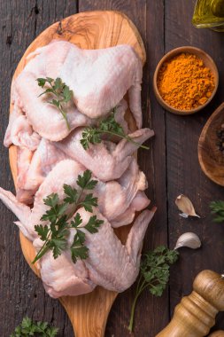 Pişirmek için malzemeli çiğ tavuk kanadı: hohey, portakal meyvesi, sarımsak, zeytin yağı, ahşap zemin üzerinde kari. Üst görünüm .
