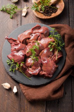 Tahta tahtada çiğ tavuk ciğeri ve ahşap arka plan. Bitki maydanozu ve biberle süslenmiş. Yiyecek malzemesi.