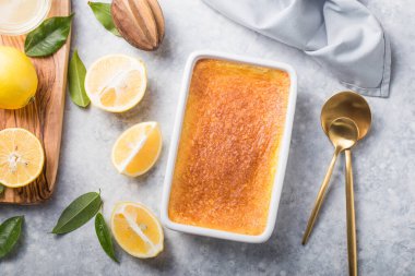Ev yapımı güveç, puding, cheesecake, turta, turta ya da krema. Taze limon ve gri taşlı arka planda yapraklar. Meyveler ve dilimler düz yerde. Citrus arkaplanı, kopyalama alanı