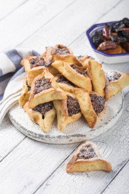 Geleneksel Yahudi Hamantaschen kurabiyeleri, kurutulmuş kayısılar, hurma. Purim kutlaması konsepti. Karnaval tatil geçmişi. Seçici odaklanma. Boşluğu kopyala.