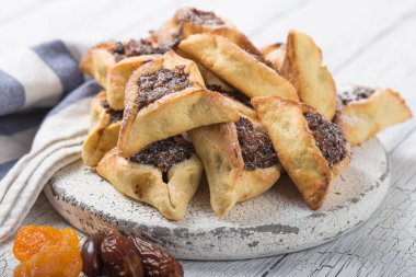 Geleneksel Yahudi Hamantaschen kurabiyeleri, kurutulmuş kayısılar, hurma. Purim kutlaması konsepti. Karnaval tatil geçmişi. Seçici odaklanma. Boşluğu kopyala.