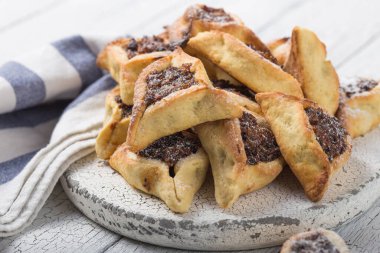 Geleneksel Yahudi Hamantaschen kurabiyeleri, kurutulmuş kayısılar, hurma. Purim kutlaması konsepti. Karnaval tatil geçmişi. Seçici odaklanma. Boşluğu kopyala.