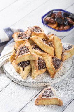 Geleneksel Yahudi Hamantaschen kurabiyeleri, kurutulmuş kayısılar, hurma. Purim kutlaması konsepti. Karnaval tatil geçmişi. Seçici odaklanma. Boşluğu kopyala.