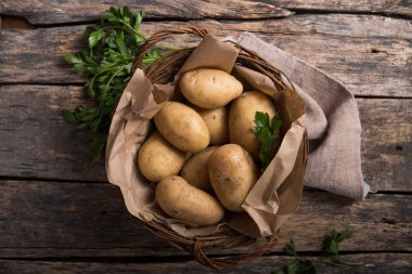 Tahta masa manzarasında maydanozlu çiğ organik patates.