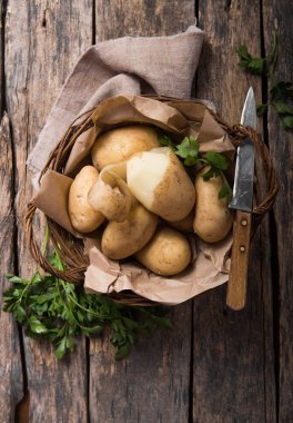 Tahta masa manzarasında maydanozlu çiğ organik patates.