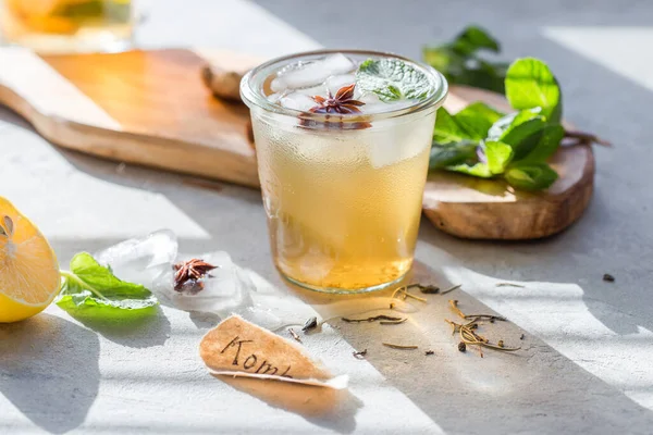 Kombucha Tea or iced tea beverage. Fermented Super Food, Pro Biotic summer  drink In Glass with mint , Lemon, On concrete  Table, outdoor. Copy space.