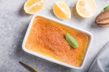 Ev yapımı güveç, puding, cheesecake, turta, turta ya da krema. Taze limon ve gri taşlı arka planda yapraklar. Meyveler ve dilimler düz yerde. Citrus arkaplanı, kopyalama alanı