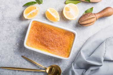 Ev yapımı güveç, puding, cheesecake, turta, turta ya da krema. Taze limon ve gri taşlı arka planda yapraklar. Meyveler ve dilimler düz yerde. Citrus arkaplanı, kopyalama alanı