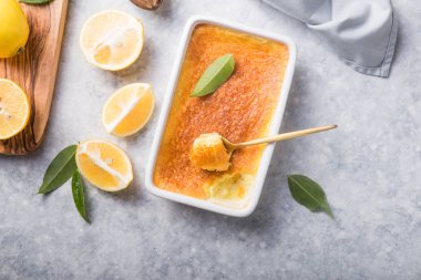 Ev yapımı güveç, puding, cheesecake, turta, turta ya da krema. Taze limon ve gri taşlı arka planda yapraklar. Meyveler ve dilimler düz yerde. Citrus arkaplanı, kopyalama alanı
